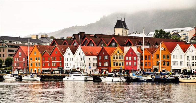 Casas coloridas do bairro histórico de Bryggen refletidas no porto de Bergen, na Noruega