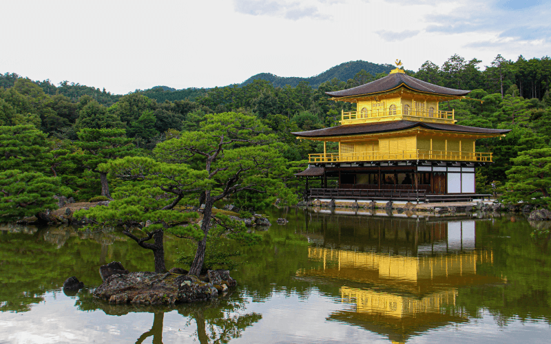 Templo dourado Kinkaku-ji em Kyoto refletido em lago rodeado por natureza