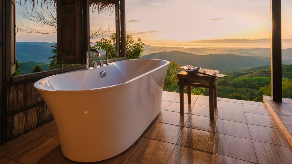 Banheira de imersão em varanda aberta com vista panorâmica para as montanhas de Chiang Rai ao entardecer, na Tailândia