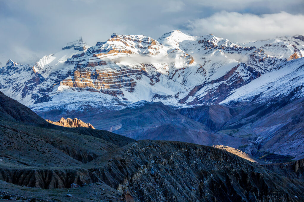 Paisagem dos Himalaias cobertos de neve com picos rochosos e céu nublado, destino de retiro de meditação e wellness