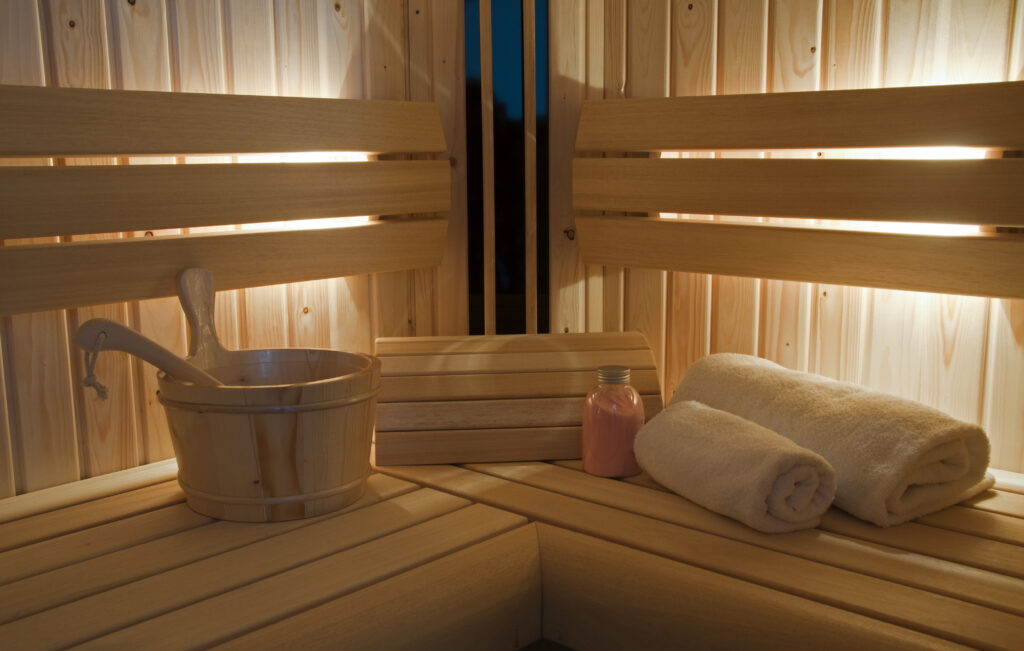 Interior de sauna de madeira com balde, toalhas e produtos de spa em retiro de wellness de luxo