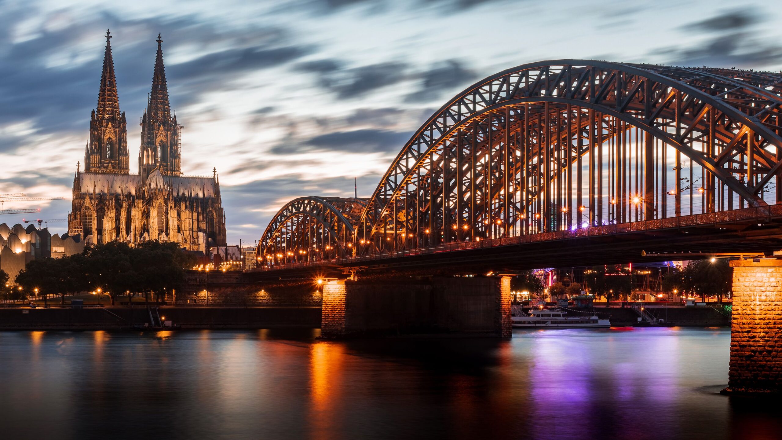 Barco de passeio Köln-Düsseldorfer ancorado no Rio Reno com igreja histórica e arranha-céus modernos ao fundo em Colônia
