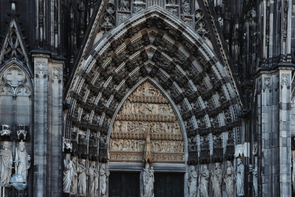 Detalhe do portal principal da Catedral de Colônia com arcos góticos e esculturas de santos em pedra